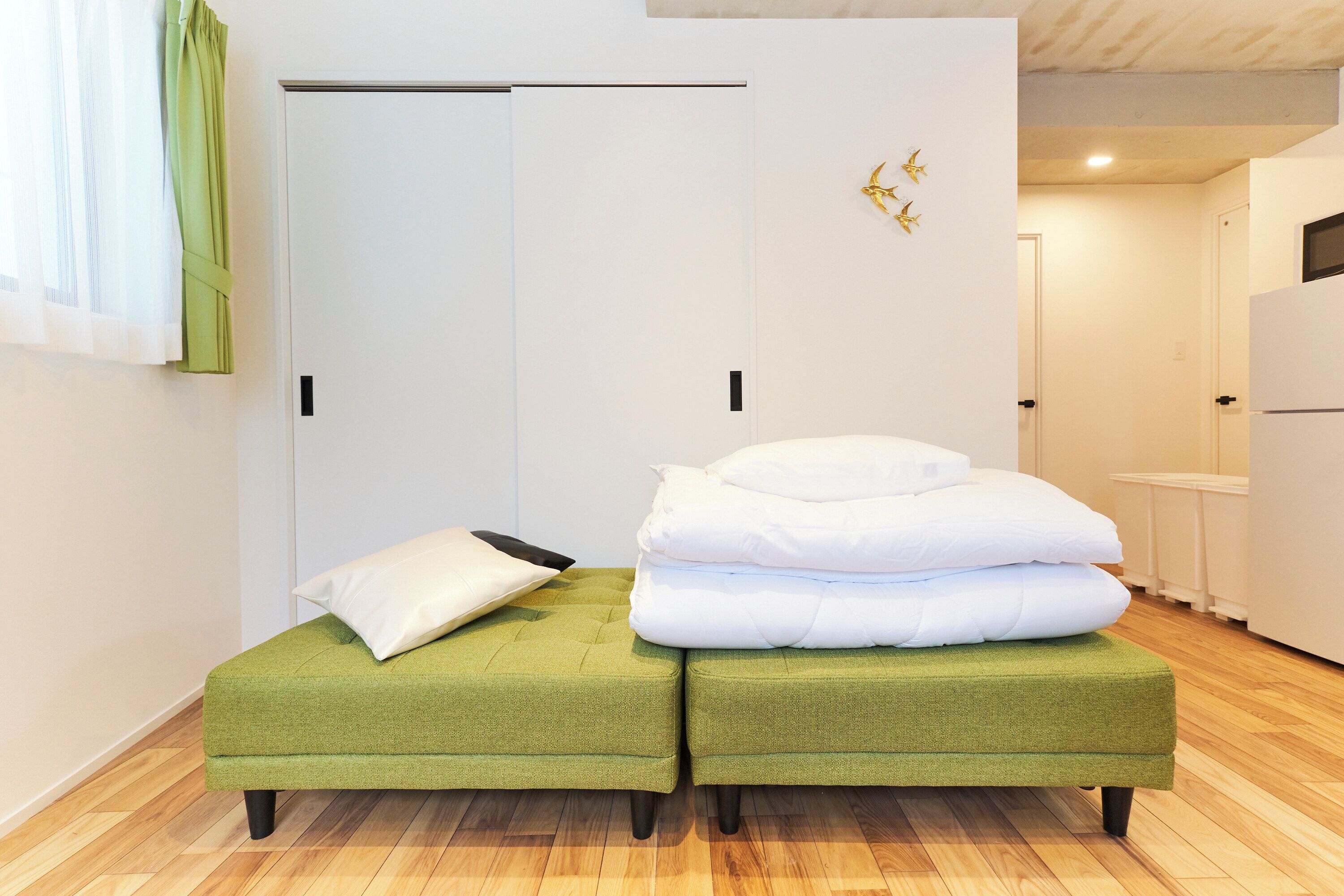 Una stanza con due pouf verdi, una porta bianca e una parete bianca decorata con elementi dorati.