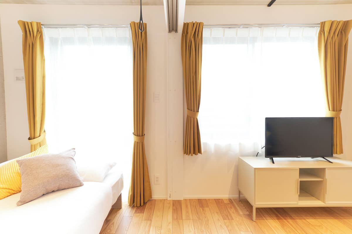 A room with a bed, a TV on a stand, and curtains.