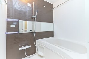 A bathroom with a bathtub, a shower, a mirror, and a towel rack. - DeLCCS Ryogoku 2 (Sumida City)