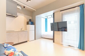 A modern hotel room with a kitchenette, a flat-screen TV, a bed, and a large window with curtains. - DeLCCS Ryogoku 2 (Sumida City)