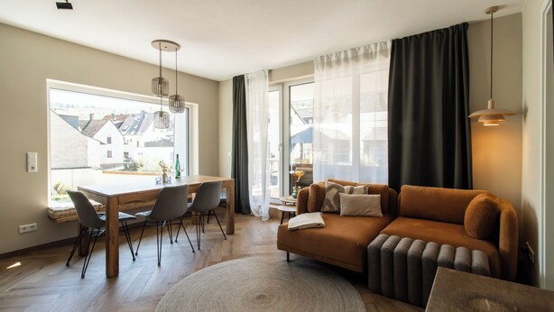 A modern living room with a sofa, dining table, chairs, and a large window with curtains. - Cozy new apartment with small balcony and great bathroom (Bremm)