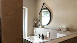 A bathroom with a white sink, black faucet, and a round mirror with a black frame. - Cozy new apartment with small balcony and great bathroom (Bremm)