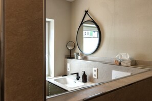A bathroom with a white sink, black faucet, and a round mirror with a black frame. - Cozy new apartment with small balcony and great bathroom (Bremm)