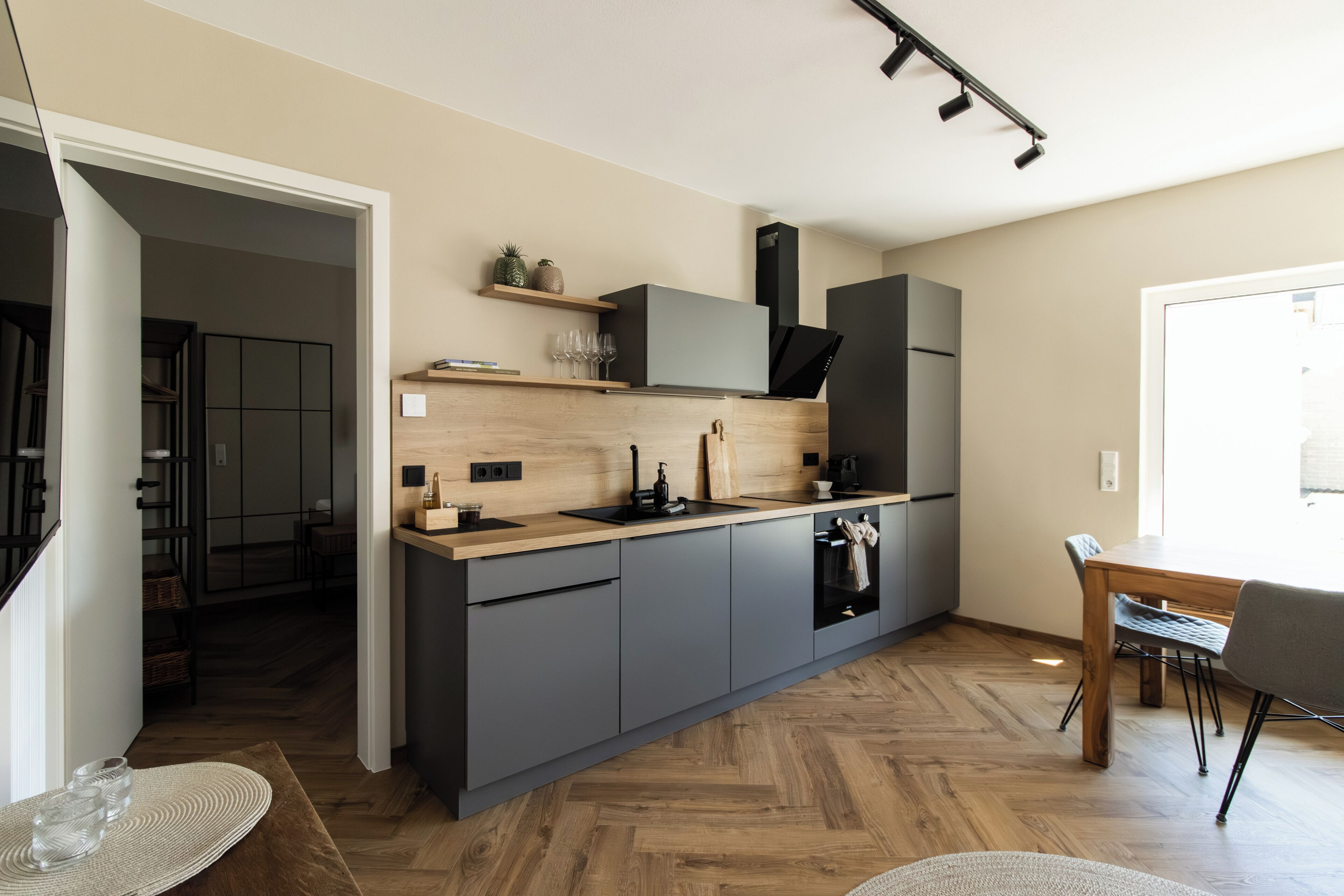 Eine moderne Küche mit grauen Schränken, einer Holz Arbeitsplatte und einem eingebauten Backofen.
