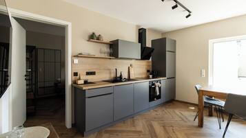 Eine moderne Küche mit grauen Schränken, einer Holz Arbeitsplatte und einem eingebauten Backofen.