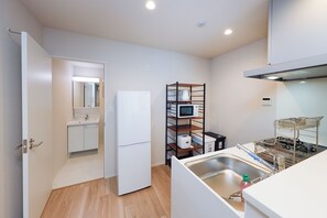 Una cocina compacta con refrigerador, microondas y escurreplatos.