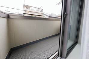 A balcony with a metal grid floor, a concrete wall, and a glass door. - La Terrasse Higashikomagata by Tranova 2 (Sumida City)