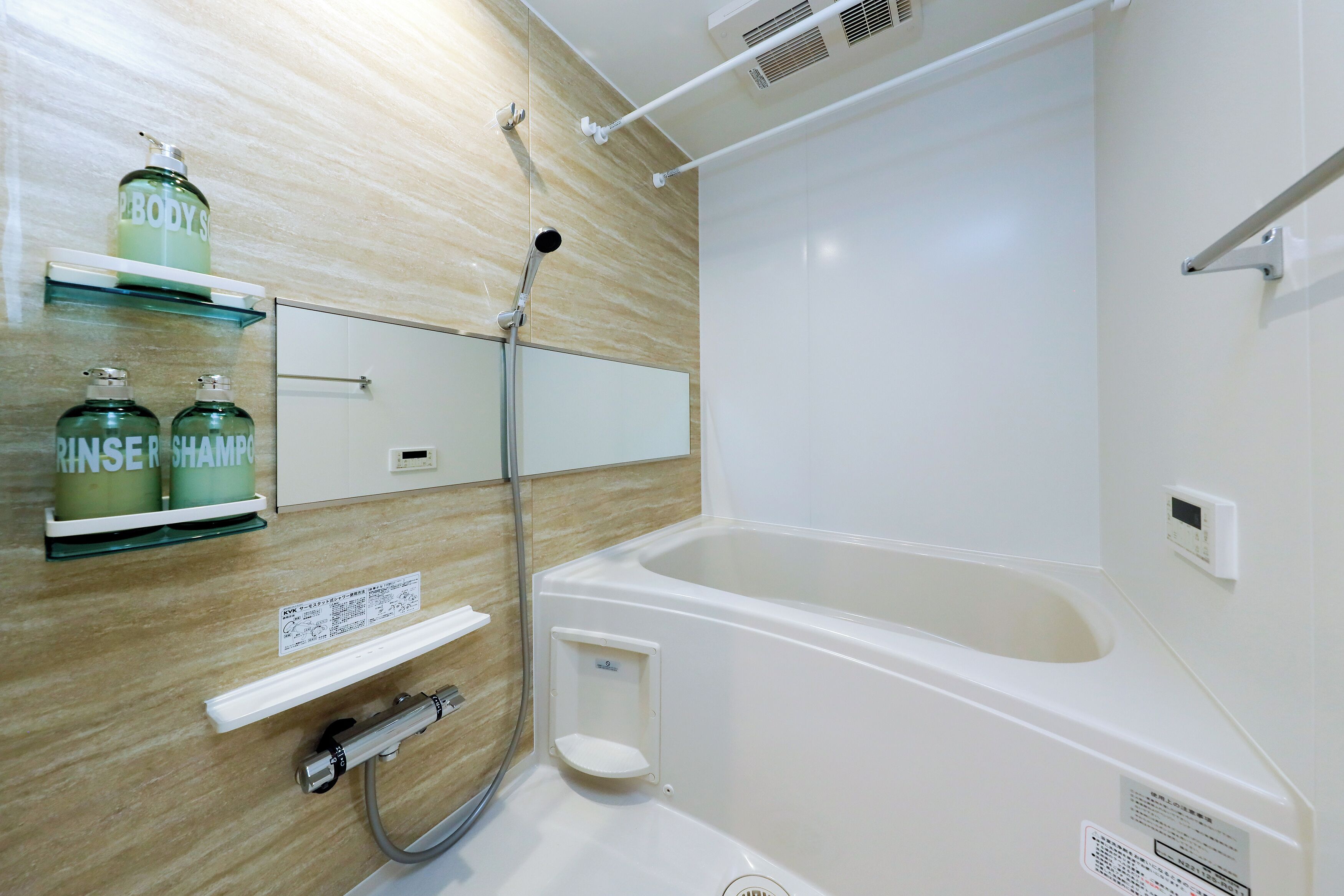 A bathroom with a bathtub, a shower, and two bottles of body wash on a shelf.