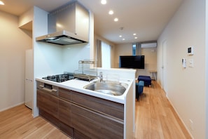 A modern kitchen with a built-in stove, a sink, and a large window. - La Terrasse Higashikomagata by Tranova 2 (Sumida City)