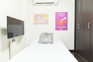 Ein Schlafzimmer mit einem Bett, einem Fernseher, einem flauschigen Kissen und zwei Bildern an der Wand.