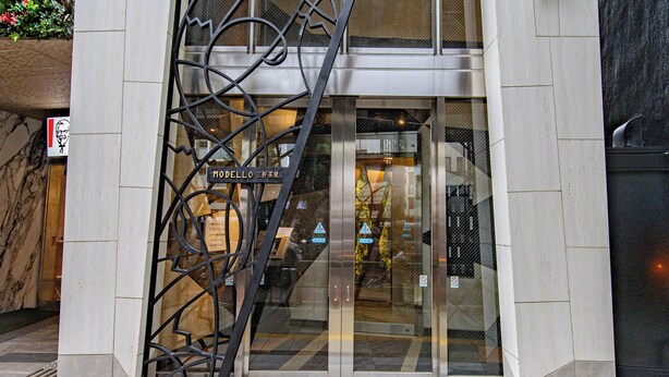 A modern building entrance with a metal gate, a sign indicating 'Motel de Oro,' and a glass door reflecting the interior. - MODELLO Sangenjaya by Tranova 2 (Setagaya City)