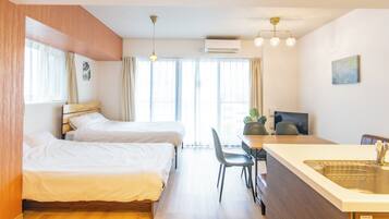 A hotel room with two beds, a desk with a chair, a sink, and a television.