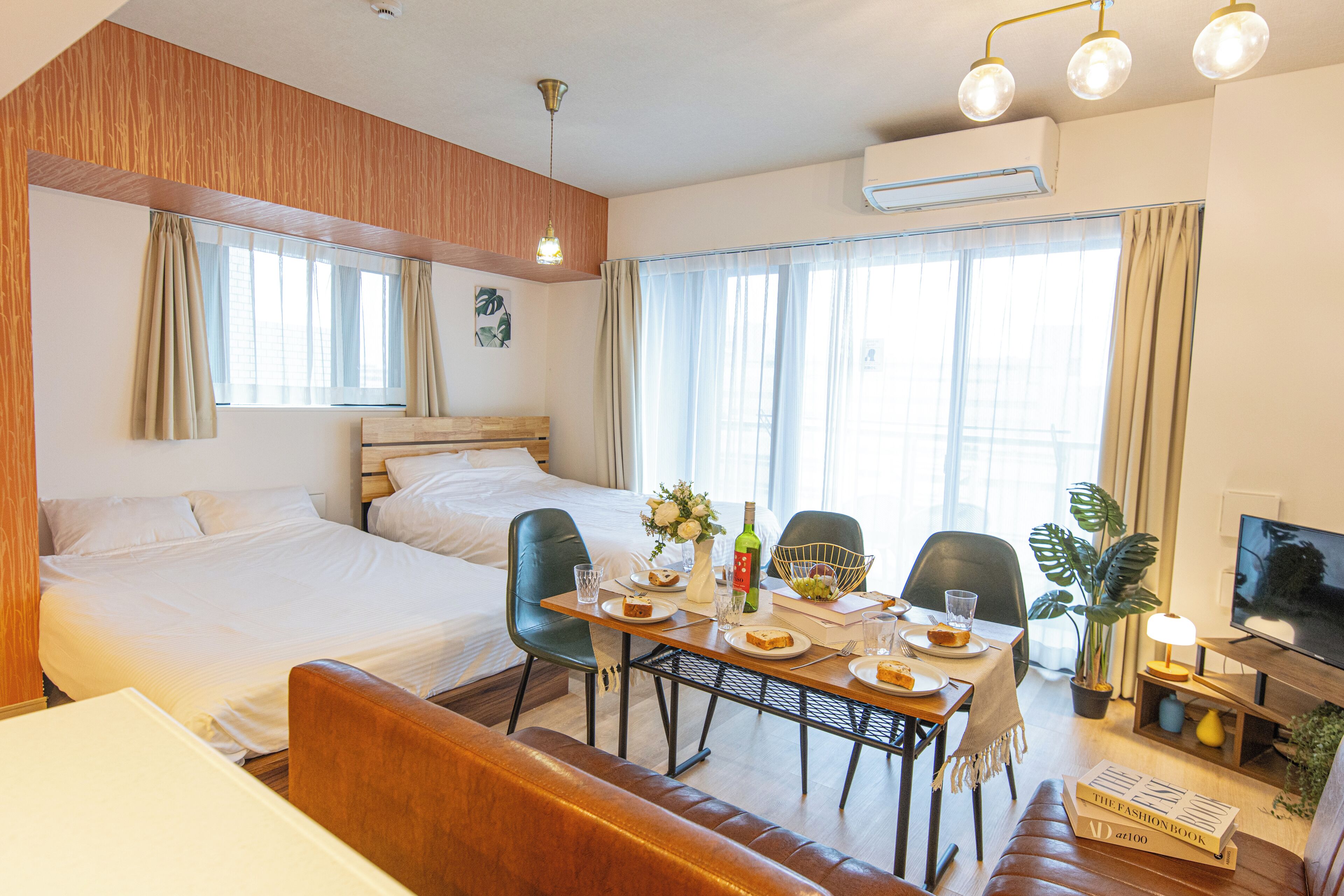 Habitación de hotel con cama, una mesa de comedor con sillas, televisión y planta en maceta.
