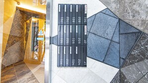 A hotel lobby with a geometric tile floor, a glass partition, and a row of numbered black lockers. - MODELLO Sangenjaya by Tranova 2 (Setagaya City)