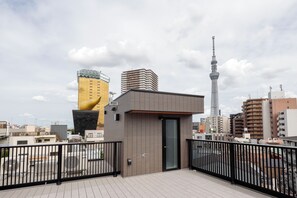 Un bâtiment moderne doté d’une porte en verre et d’une rambarde en métal, entouré d’un paysage urbain composé de différents immeubles et d’une tour.