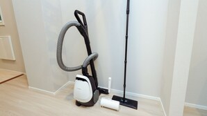 A vacuum cleaner with a hose and a mop attachment, a power strip, and a wall-mounted vent. - AI Grandir Azumabashi 2 (Sumida City)