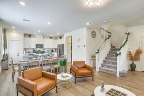 Een moderne woonkamer met leren banken, een eettafel en een keuken op de achtergrond.