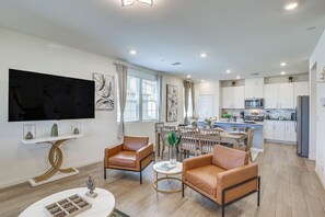 Een moderne woonkamer met leren fauteuils, een salontafel en een flatscreen televisie.