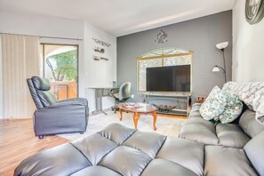 Ein modernes Wohnzimmer mit einer Ledersofa, einem Couchtisch, einem Fernseher und einem großen Fenster.