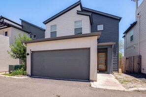 Ein Wohngebäude mit Garage, Hauseingang und kleiner Veranda.