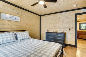 Un dormitorio con cama, cómoda, ventilador de techo y un cartel en la pared.