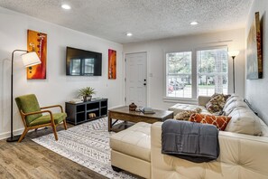A living room with a sofa, armchair, coffee table, and artwork on the walls. - < 2 Mi to Dallas Stadium! Work & Play Base w/ Yard (Arlington)