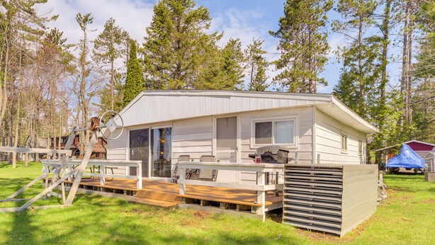 A single-story RV with a covered deck, a small porch, and a windowed front door.