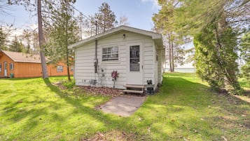 A small, single-story cabin with a front door, a small porch, and a window.