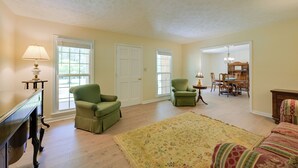 A room with a green armchair, a floral rug, a wooden desk, and a dining area with chairs and a table. - Dublin Retreat Near Golf, Weddings & Tournaments (Dublin)