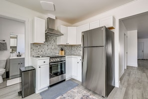 A modern kitchen with white cabinets, a stainless steel refrigerator, a built-in oven, and a tiled backsplash. - Updated + Modern Craftsman Bungalow in Renton! (Renton)