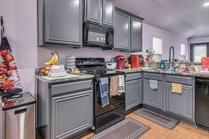 Una cocina con gabinetes grises, un microondas, una estufa y una cafetera.