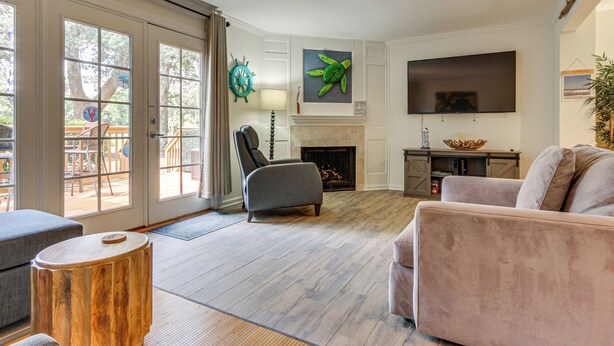 A living room with a fireplace, a television, and a large window. - Relax Poolside! Golfer’s Paradise in Hilton Head (Hilton Head Island)
