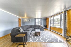 Ein modernes Wohnzimmer mit einem Ecksofa, einem kleinen Couchtisch und einem gemusterten Teppich.