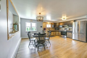 Eine Küche mit Holzboden, einem Esstisch mit Stühlen, einem Kühlschrank und einer Pendelleuchte.