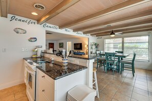 A kitchen with a granite countertop, white cabinets, and a dining area with a table and chairs. - Johnson Bay Hideaway: Bayfront Naples Home w/ View (Naples)
