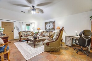 A living room with a sofa, coffee table, and a desk with a chair. - 4 Mi to Lake Houston! Single-Level Home w/ Yard (Humble)