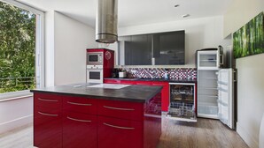 Una cocina moderna con armarios rojos, horno empotrado, microondas y lavavajillas.
