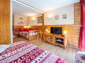 Ein Zimmer mit Holzboden, einem Bett, einem Fernseher und einem Schreibtisch.