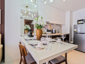 Eine moderne Küche mit Essbereich, gedeckter Tafel, einer großen Kochinsel, Edelstahlgeräten und einer Vase mit Blumen.