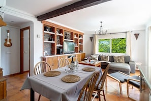 A dining area with a table set for four, a kitchen with brick shelving, and a living area with a sofa and window. - Tahiti 2 7 by Casasol (Nerja)