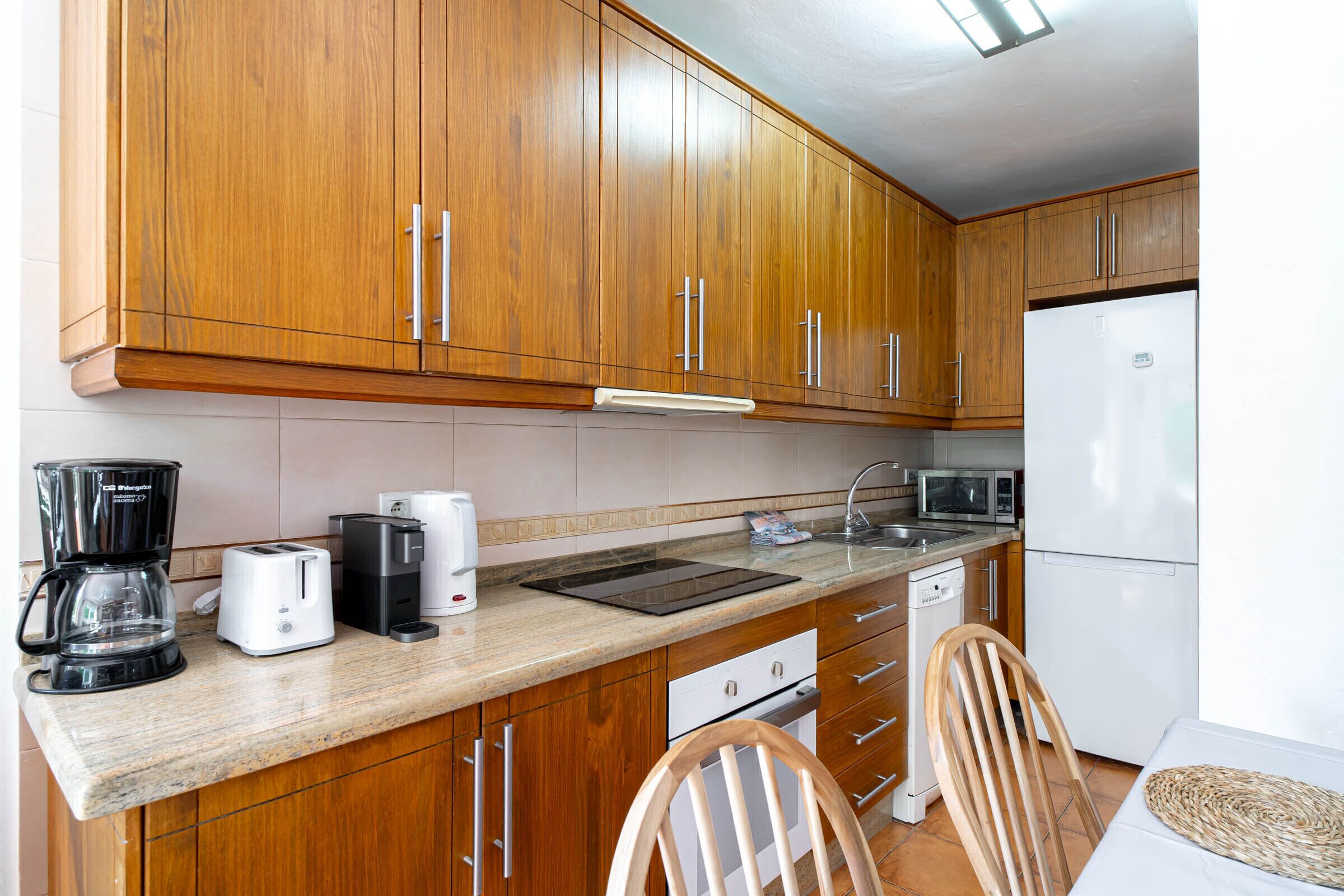 A kitchen with wooden cabinets, a microwave, a toaster, and a coffee maker.