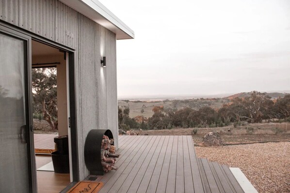 A modern building with a wooden deck and a view of the countryside.
