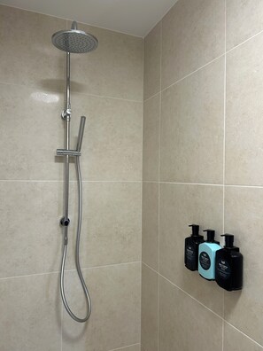 A shower with a handheld showerhead and a handheld faucet.