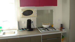 Una cocina con microondas, estufa, fregadero y armarios rojos.