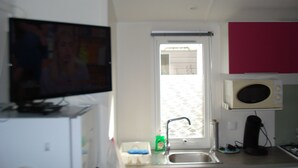 Una cocina compacta con un lavamanos, un microondas y un televisor.