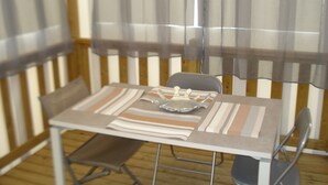 Una mesa de comedor con sillas, mantel y una ventana con cortinas.