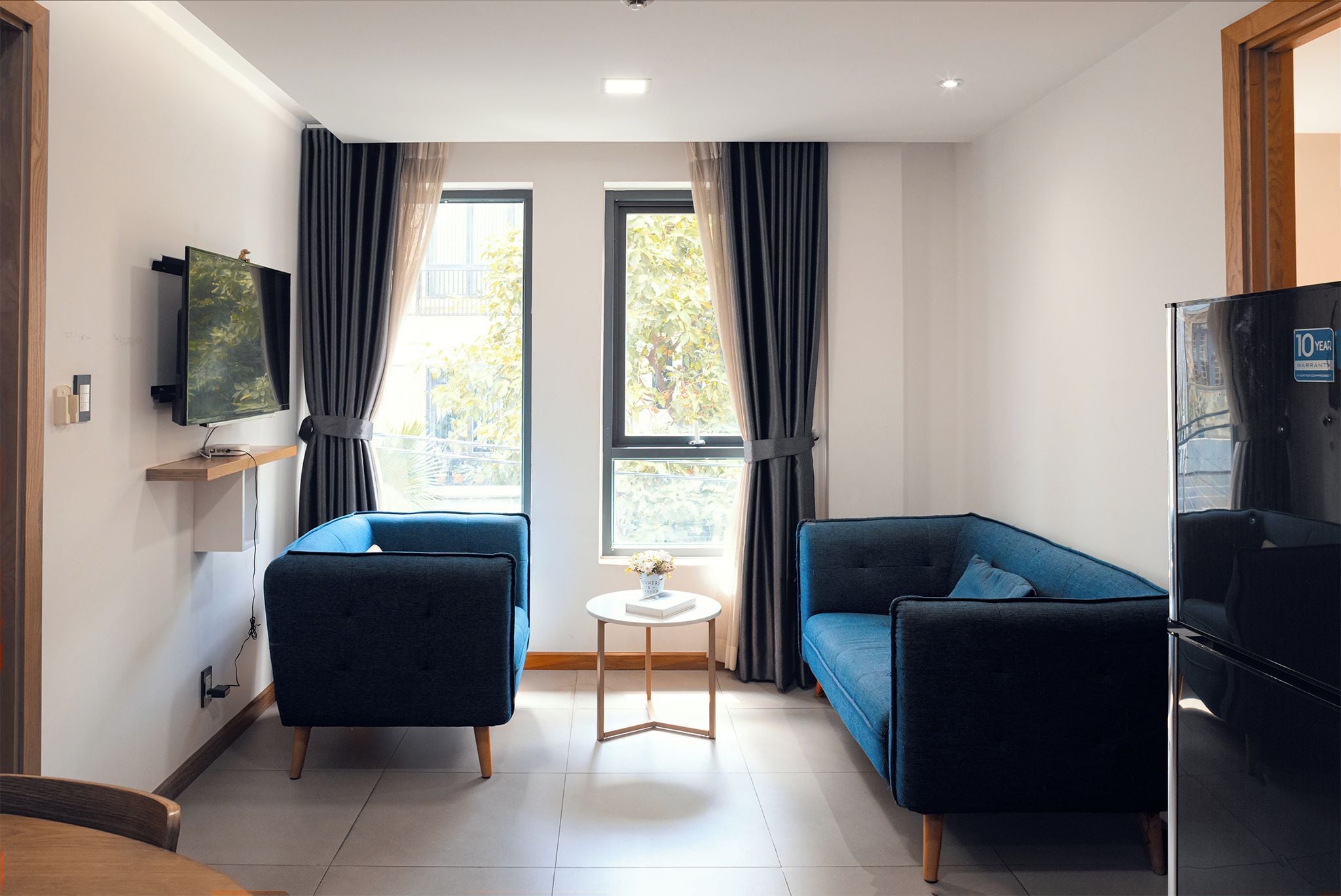 Un salon moderne comprenant un canapé, un fauteuil, une petite table et un téléviseur.