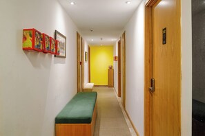 Um corredor com um banco, portas de madeira e uma parede amarelo-vivo.