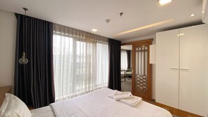 Habitación de hotel con una cama grande, un armario y vistas a través de la ventana.
