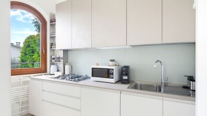 A modern kitchen with white cabinets, a built-in microwave, a gas stove, and a stainless steel sink. - Casa Del Paperotto (Peschiera del Garda)